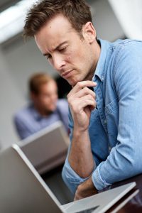 Guy thinking intently in front of laptop